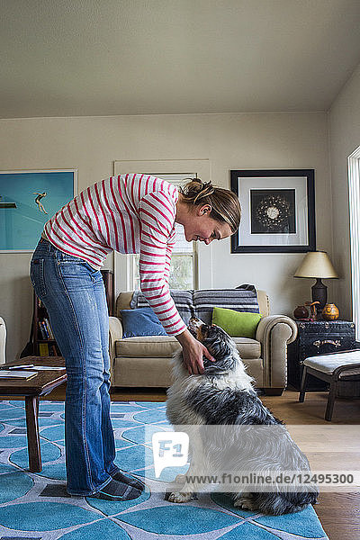 A young dog owner enjoys time with his dog in their home.