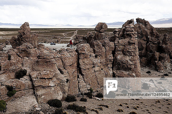 Ein junger Mann spielt auf den Felsen in der Atacama-Wüste. Der Salar de Uyuni ist die größte Salzfläche der Welt und beherbergt eines der größten Lithiumvorkommen der Welt. Die Gemeinden in der Umgebung dieser Region könnten von der Erschließung und dem Abbau stark profitieren oder darunter leiden.