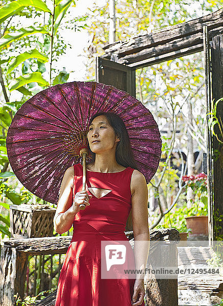 Schöne Frau in rotem Kleid im traditionellen Thai-Haus
