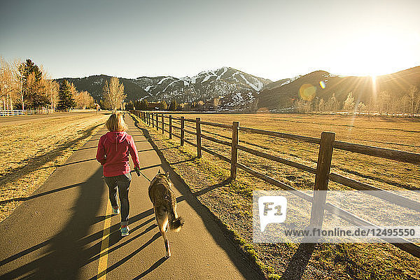 Ein Mädchen  das mit ihrem Hund an einem sonnigen Frühlingstag in Sun Valley  Idaho  USA  spazieren geht