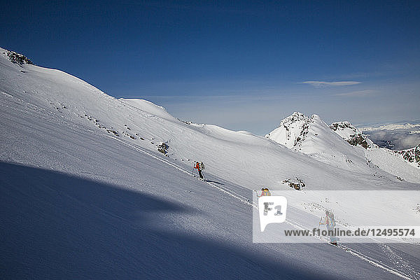 Skifahrer erklimmen eine Piste auf dem Gipfel eines Berges in Whistler  British Columbia  Kanada.