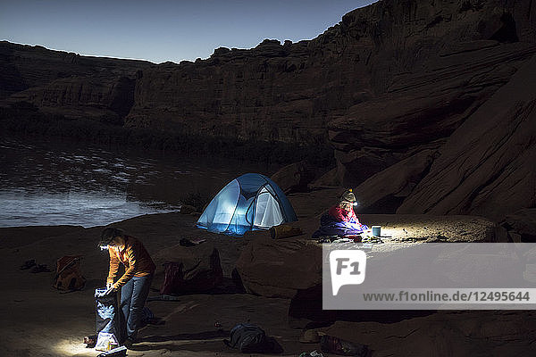 A mother and daughter getting ready for bed in a tent while camping on sandstone along the Labyrinth Canyon section of the Green RIver  Green River  Utah.