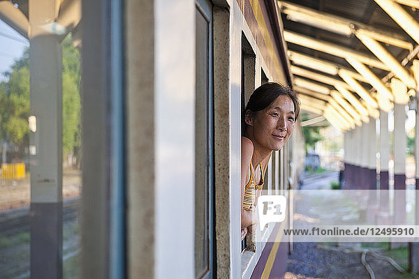 woman leaning out of train window in Chiang Mai in northern Thailand