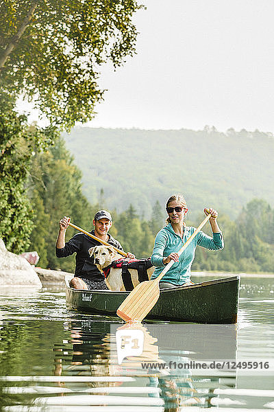 Man And Woman Enjoying Canoeing With Their Dog On Caspian Lake