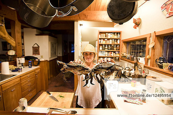 Ein Mädchen hält zwei Krabben in der Küche  bevor sie gekocht werden