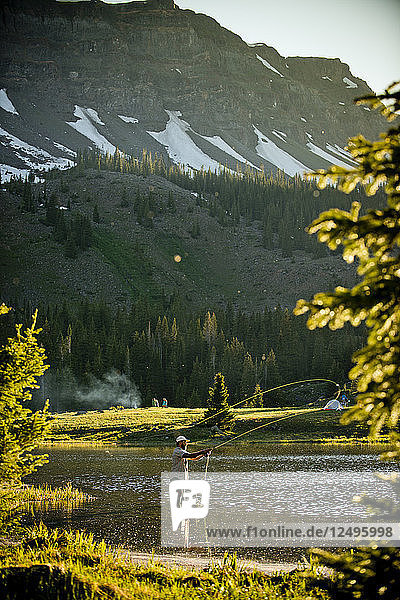 A fly fisherman in a high alpine lake at sunset in Yampa Colorado.