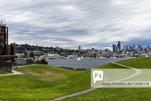 A woman rides her cruiser bike at Gasworks Park in Seattle  Washington on a cloudy day.