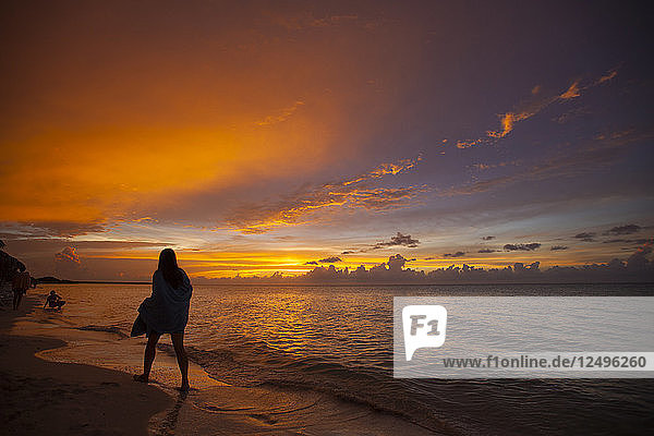 Eine in ein Handtuch eingewickelte junge Frau geht kurz nach Sonnenuntergang am Strand von Cayo Coco  Kuba  spazieren.