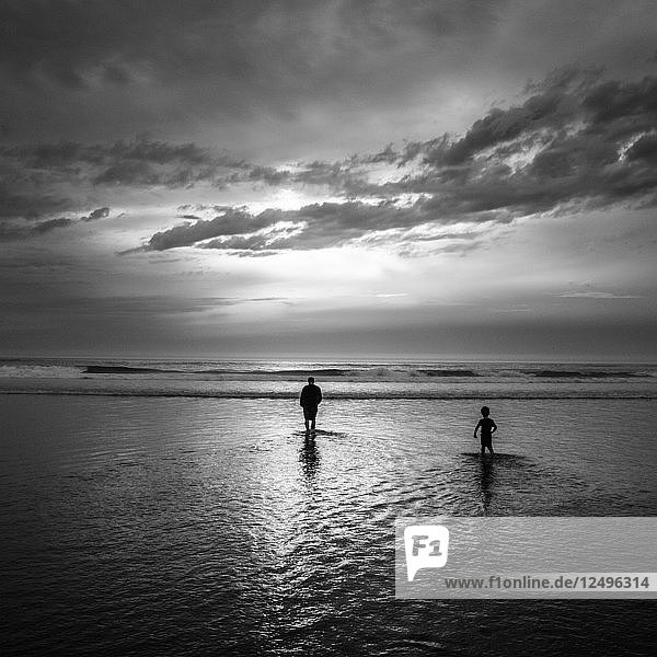 Ein Vater und sein Sohn waten in den Pazifik  während sie am Rockaway Beach in Oregon Urlaub machen.