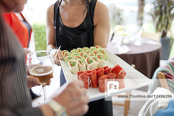A server presents hors d'oeuvres to guests at a party.