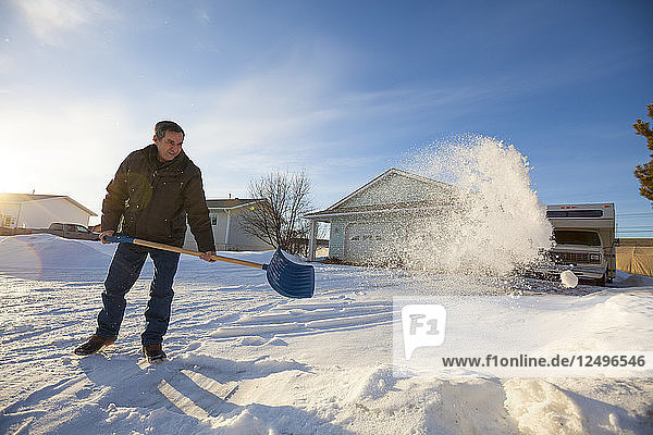 Ein Mann schaufelt in Nord-Alberta den Schnee von seiner Einfahrt.