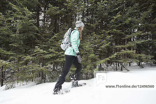 Frau beim Schneeschuhwandern in den Wäldern.