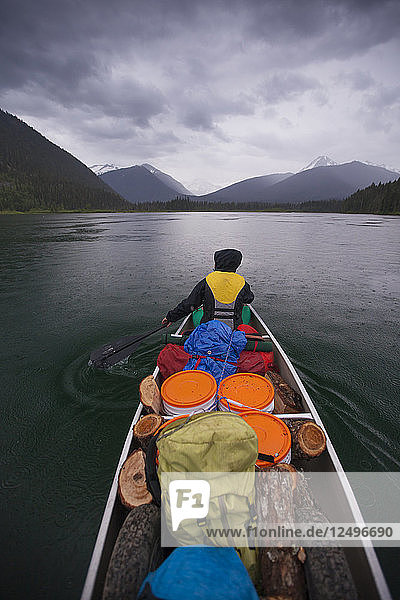 Canoeing in the rain across McLeary Lake during a multi-day canoe trip through Bowron Lake Provincial Park  British Columbia  Canada.