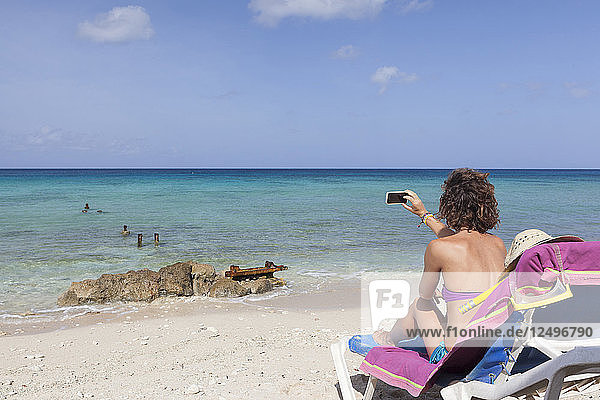 Mädchen  das beim Sonnenbaden am Strand in Kuba ein Foto macht
