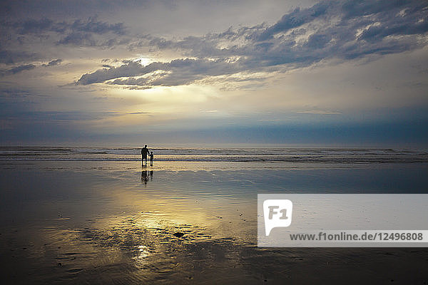 Ein Vater und sein Sohn beobachten den Sonnenuntergang während ihres Urlaubs in Rockaway Beach  Oregon.