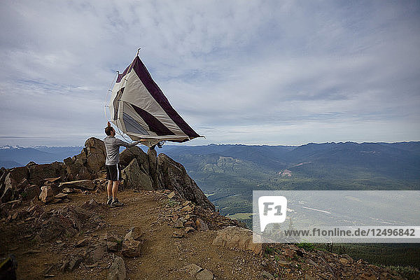 A hiker shakes his tent out after camping on the summit of Sauk Mountain  Washington.