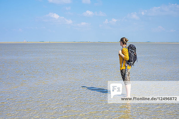 Young woman walking through the Wadden Sea (Wattenmeer) at low tide  Sankt Peter-Ording  Nordfriesland  Schleswig-Holstein  Germany