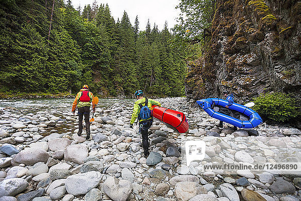 Three Men Walk Up The River In Order To Paddle A Section Of Rapids On The Chehalis River