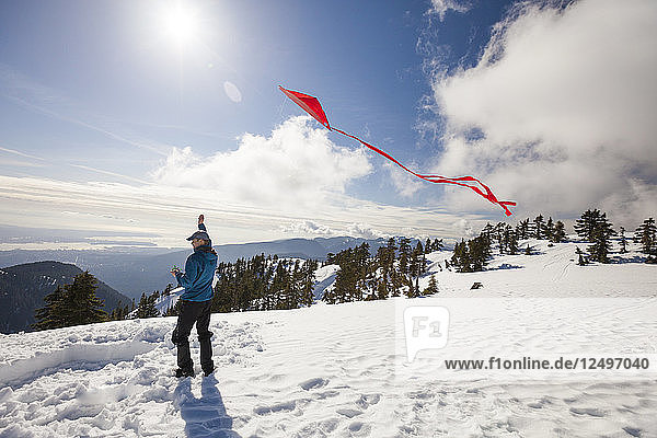 A Hiker Flying A Kite On The Top Of A Snow Covered Mountain
