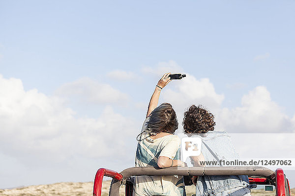 Zwei Mädchen machen ein Selfie auf dem Dach ihres Cabrio 4-Rad-Antriebs