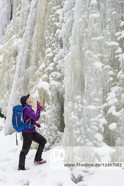 Eine Wanderin blickt auf eine hohe Wand aus Eis und Schnee.