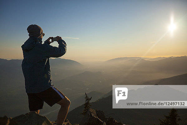 Ein Wanderer fotografiert mit seinem Smartphone die Aussicht vom Gipfel des Sauk Mountain in den North Cascades  Washington.
