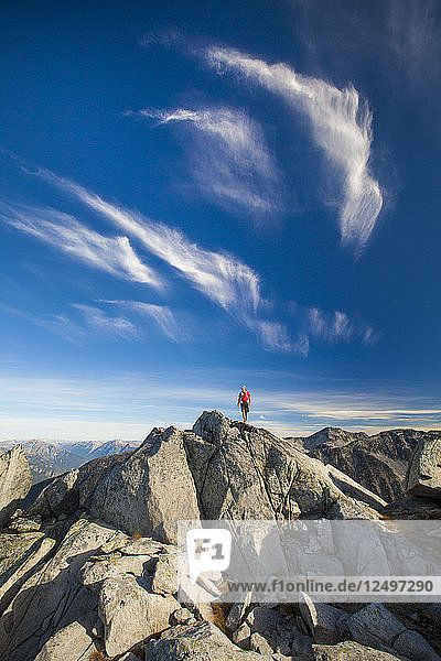 A backpacker stands on top of a rocky summit near Whistler  British Columbia  Canada.
