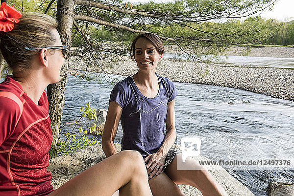Zwei Frauen hängen nach einem Trail Run am Fluss ab.