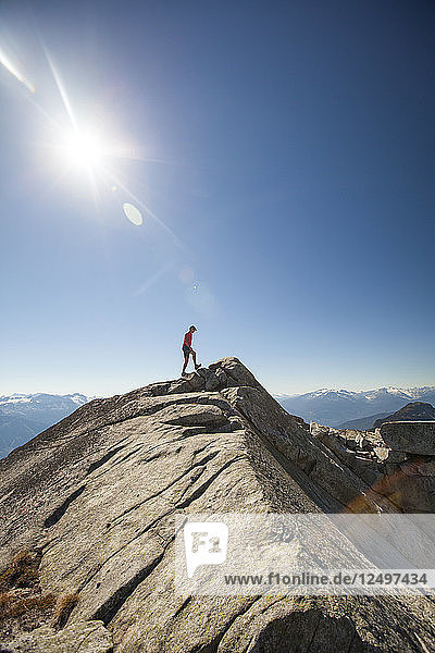 A hiker walks along a rocky ridge while on the summit of Cassiope Peak near Pemberton  British Columbia  Canada.