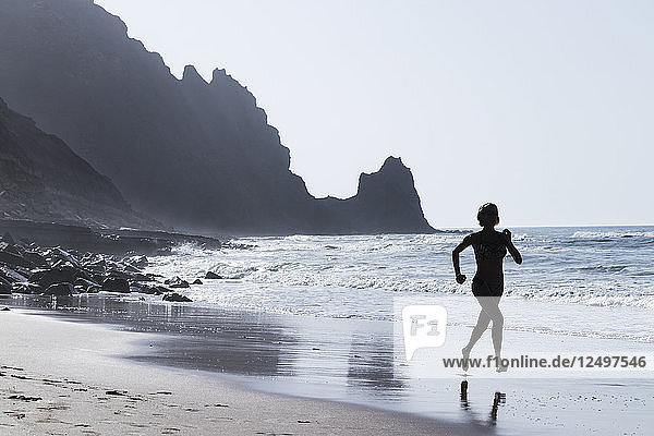 Eine Frau läuft am Strand von Luz  Portugal