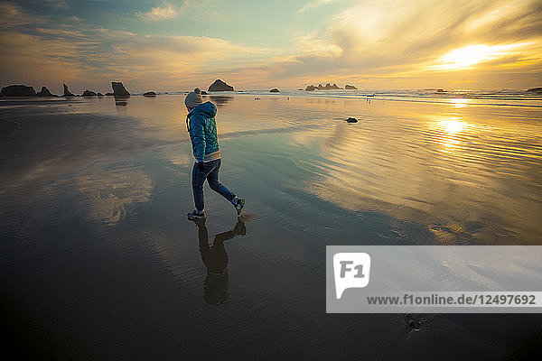 A young woman walks along Bandon Beach  Oregon.