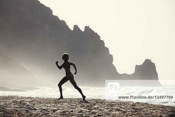 Eine Frau trainiert am Strand von Luz  Portugal