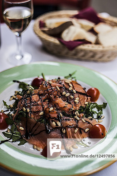 Ein Salat mit frischem Lachs und Tomaten und ein Glas Weißwein in Italien.
