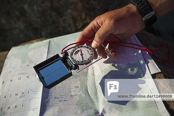A man uses a compass and paper map to navigate.