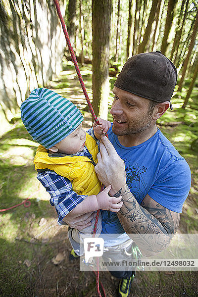 A man holds his son before rock climbing.