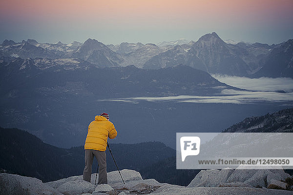 A photographer captures the blue hour from a rocky mountain ridge in Pinecone Burke Provincial Park  British Columbia  Canada.