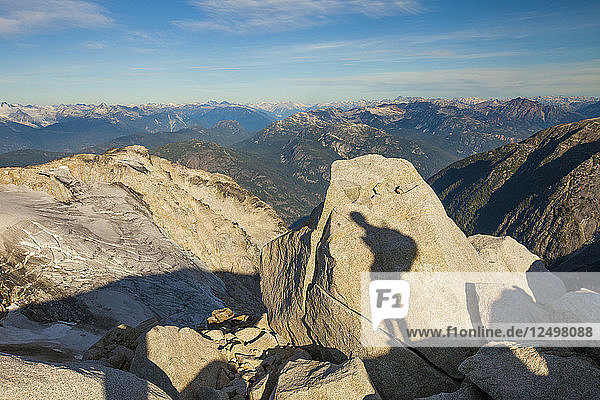 Der Schatten eines Rucksacktouristen wird auf einen großen Granitfelsen hoch in den felsigen Bergen von British Columbia  Kanada  projiziert.