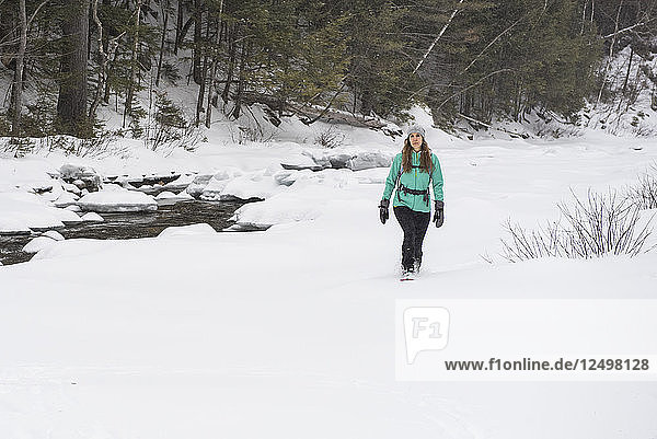 Woman hiking along river in winter