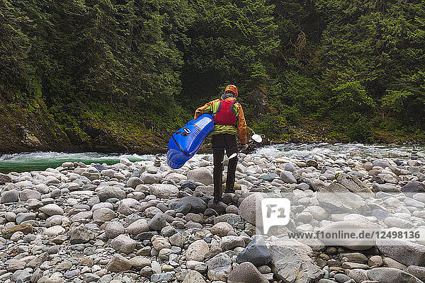 Mann trägt sein Packraft auf dem Chechalis-Fluss