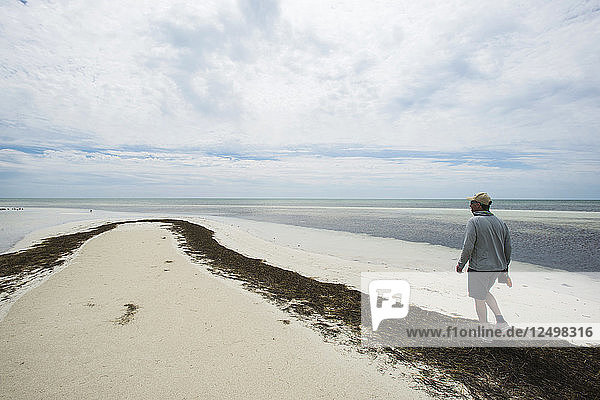 Fischer zu Fuß entlang der Unkraut bedeckten Strand in den Florida Keys