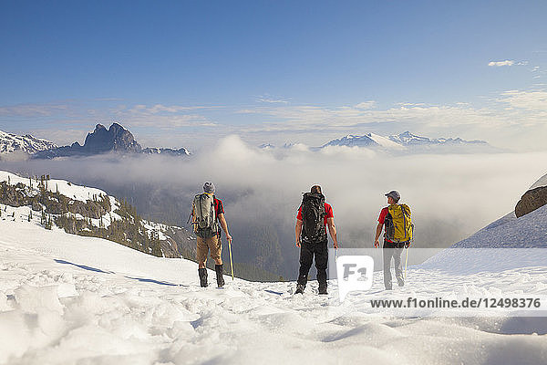 Three backpackers cross a snowfield after a trip into the mountains of British Columbia  Canada.