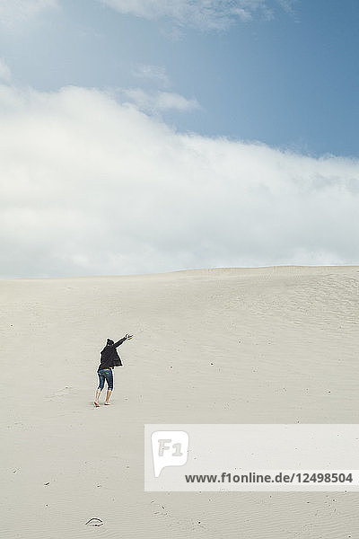 A Young Man Is Running To Reach The Top Of A Sand Dune