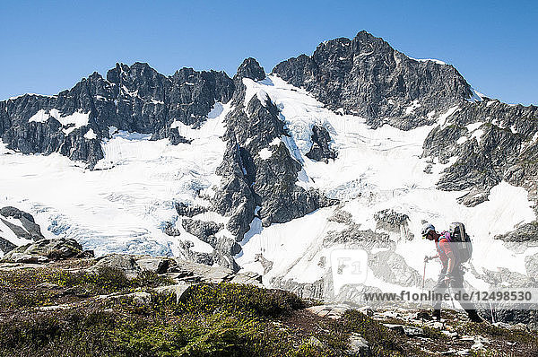 Climber traversing in front of Mount Formidable during the Ptarmigan Traverse   North Cascades  Washington