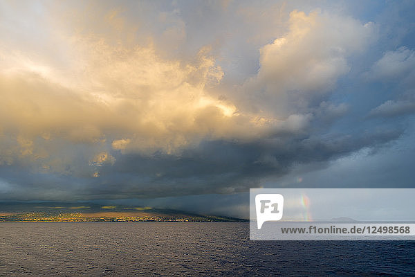 Ein Regenbogen unter einem stürmischen und bewölkten Himmel über der Insel Maui.