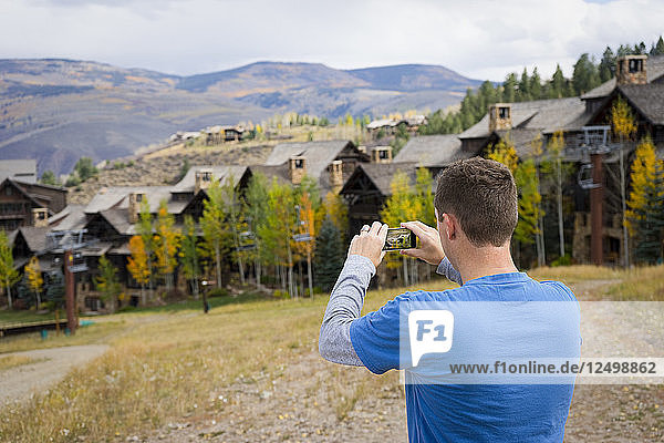 Mann nimmt ein Foto der Herbstlandschaft mit einem Smartphone auf