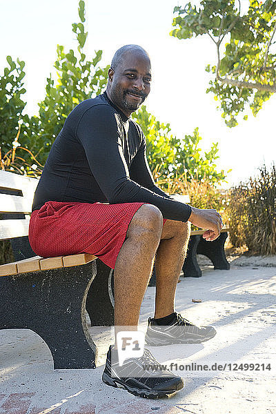 Man dressed in fitness clothing sitting on a park bench