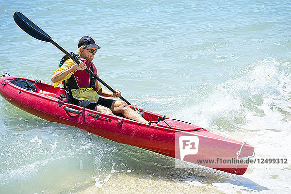 Woman paddling a kayak in a wave