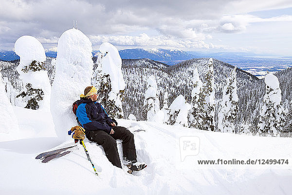 Ein männlicher Backcountry-Skifahrer macht eine Pause  nachdem er einen Bergkamm in der Whitefish Range in der Nähe von Whitefish  Montana  hochgefahren ist.