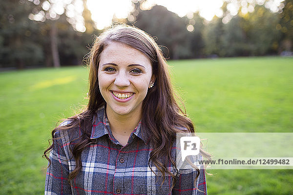 Ein weiblicher High-School-Schüler posiert für ein Porträt im Freien im Armitage Park in Eugene Oregon. Seniorenporträts sind eine beliebte Fotosession  mit der der Eintritt eines jungen Erwachsenen ins Erwachsenenalter gefeiert wird.