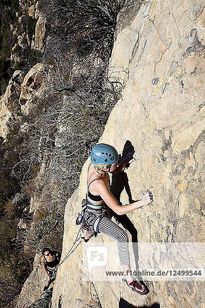 Eine Frau mit Tanktop und gestreifter Hose klettert The Rapture (5.8) am Lower Gibraltar Rock in Santa Barbara  Kalifornien. The Rapture ist eine sehr schöne und unglaublich gut abgesicherte Route auf der linken Seite des Lower Gibraltar Rock.